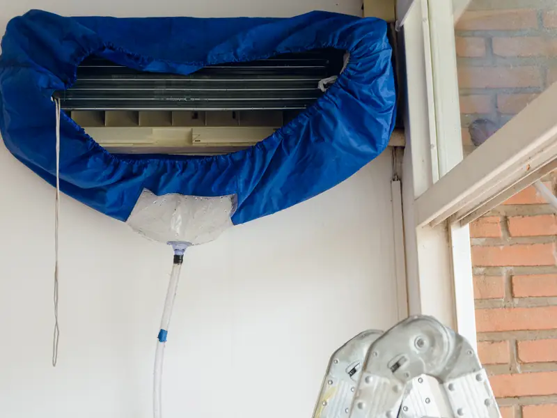 Housse de lavage fixée sous un split mural pour récupérer l'eau de nettoyage