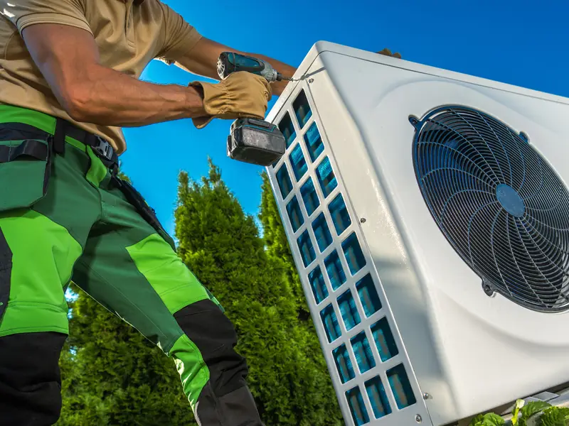 Installateur fixant le groupe extérieur d'une pompe à chaleur air-air
