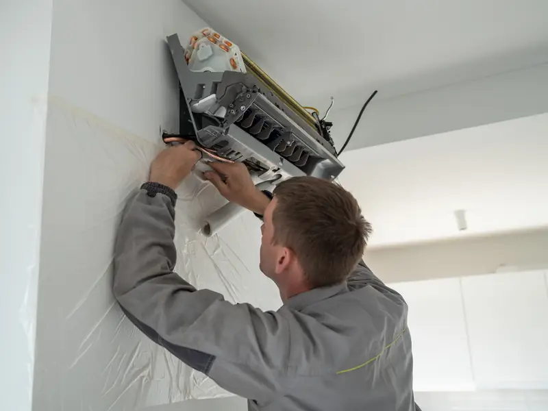 Installateur fixant au mur l'unité intérieure d'une pompe à chaleur air-air