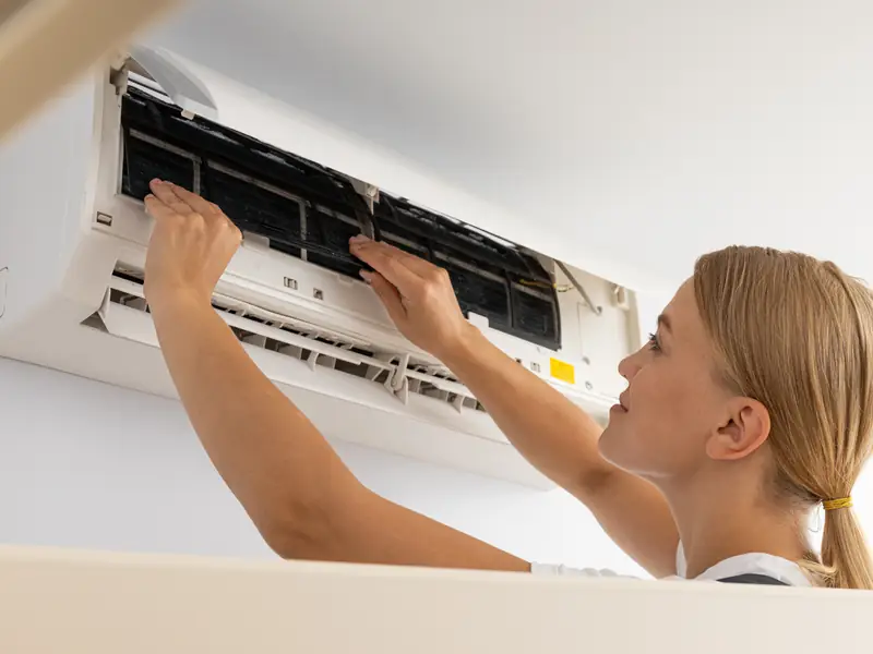 Technicien nettoyant les filtres d'un climatiseur mural pendant un entretien