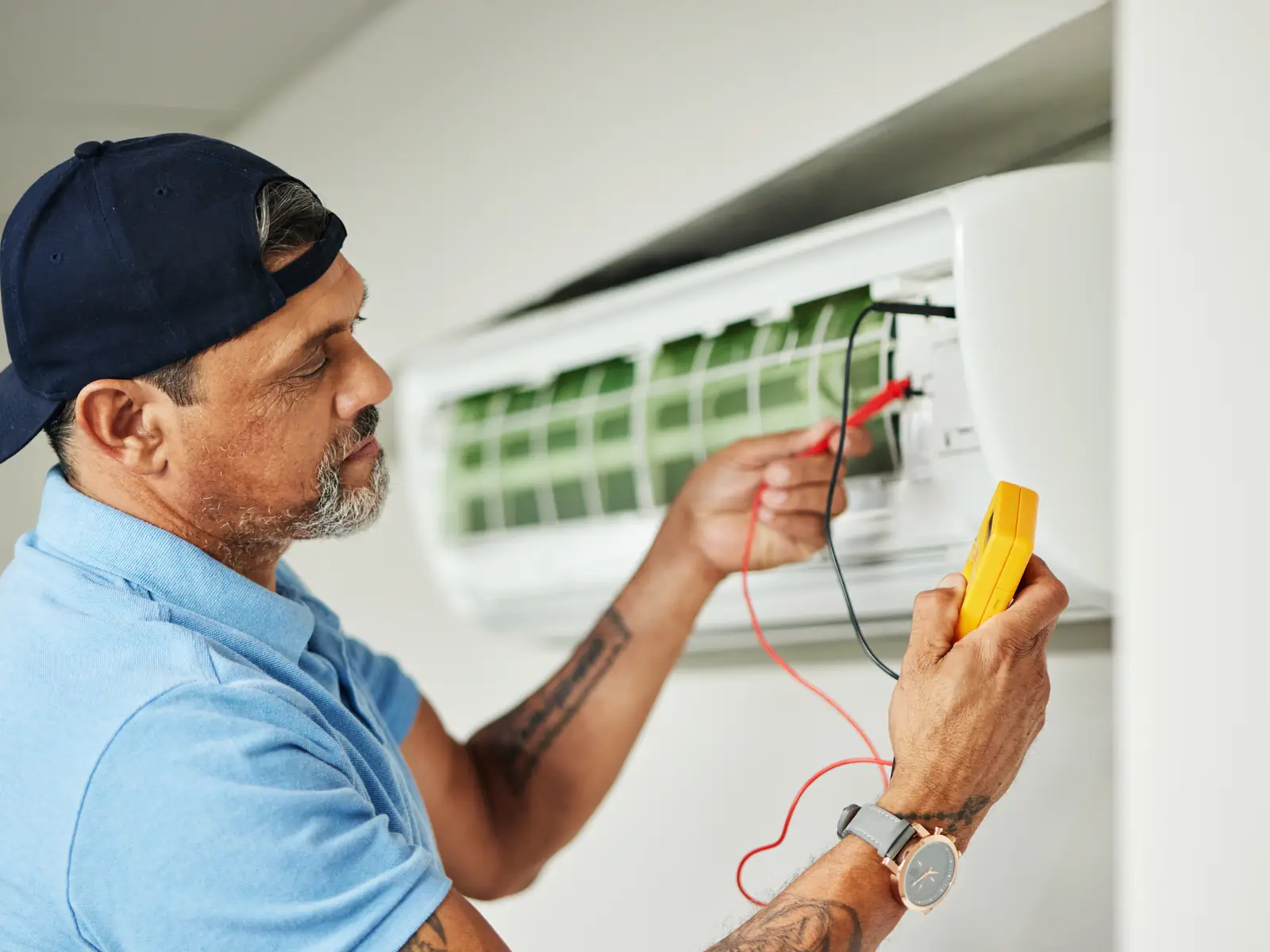 Technicien prenant des mesures au multimètre sur une unité intérieure de climatisation