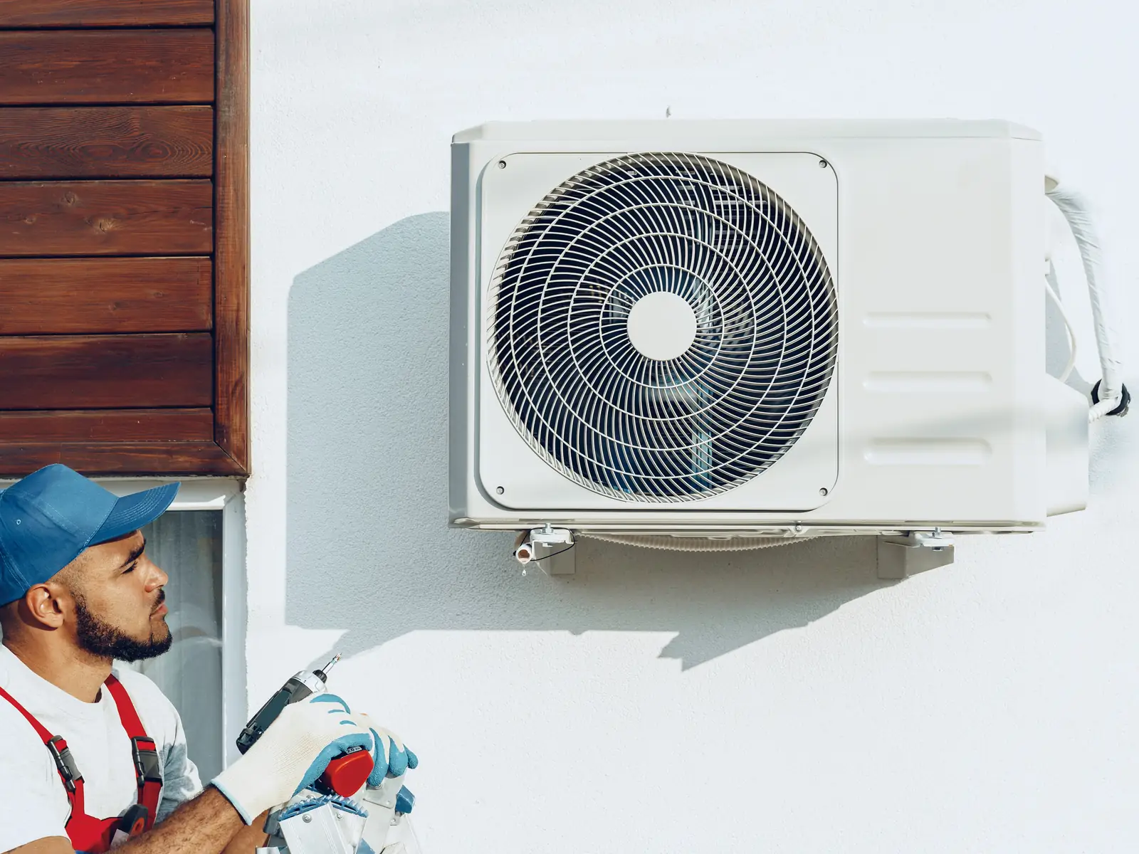 Technicien près d'un groupe extérieur de climatisation fixé au mur