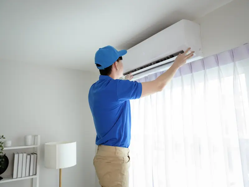 Technicien vérifiant le bon fonctionnement d'une unité murale de climatisation